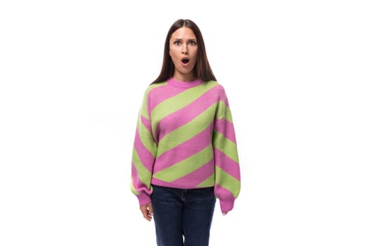 young surprised caucasian woman with black hair dressed in a pink sweater on a white background.