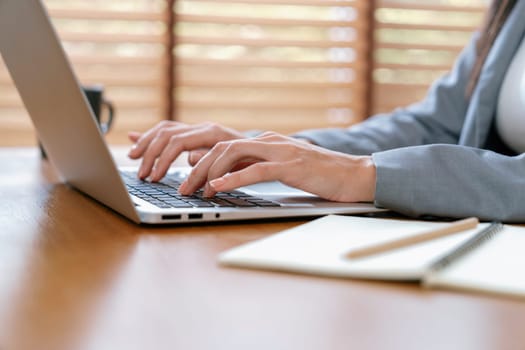 Businesswoman typing on laptop, working on business on workspace table. Young college student study or brainstorming strategic plan in office workplace for business success. Blithe