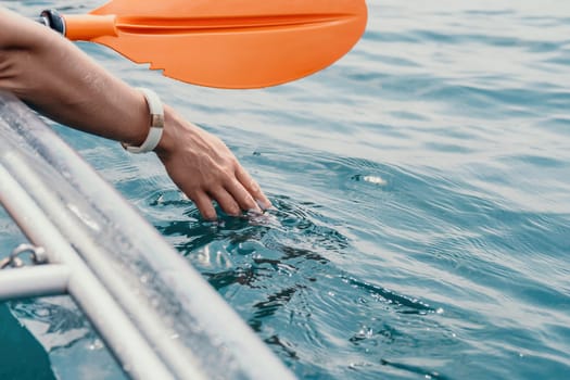 Woman in kayak back view. Happy young woman with long hair floating in transparent kayak on the crystal clear sea. Summer holiday vacation and cheerful female people having fun on the boat.