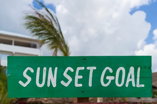 green sign with white writing "sun set goal" on sandy beach at sunny day,relax and summer concept.