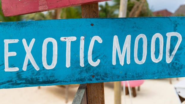 Sky-blue sign with white writing "exotic mood" on sandy beach at sunny day,relax and summer concept.