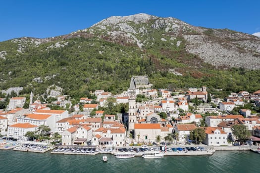 Motor boats stand off the coast of Perast against the backdrop of the Church of St. Nicholas and ancient houses. Montenegro. High quality photo