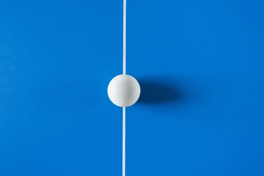 A white tennis ball for a table tennis at the blue background.