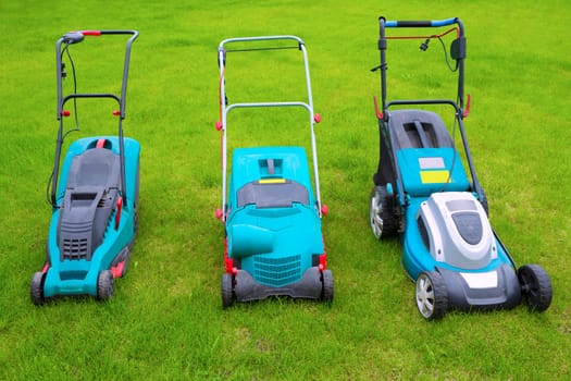 Lawn mowers standing in the backyard in a sunny summer day, a close-up.