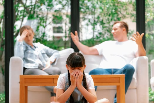 Stressed and unhappy young girl crying and trapped in middle of tension by her parent argument in living room. Unhealthy domestic lifestyle and traumatic childhood develop to depression. Synchronos