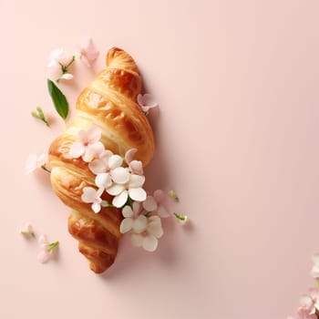 Delicious croissant with spring flowers on pink background. French traditional food concept with copy space. Top view
