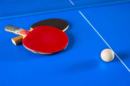 Sport games in Ping Pong. Rackets for table tennis and a ball on the blue table.