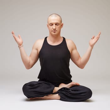 Studio photo of yoga instructor meditating, on grey background