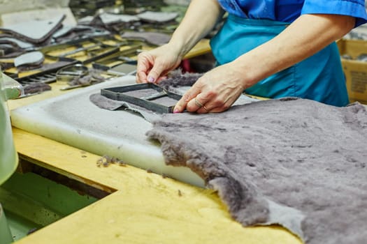 Production of fur insoles. Worker uses template, close-up