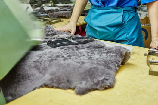 Production of footwear. Worker uses curve on pelt, close-up