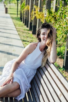 beautiful smiling woman in a summer light dress in the park on a walk