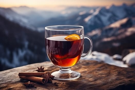 A glass of hot mulled wine with spices on a table overlooking the mountains.