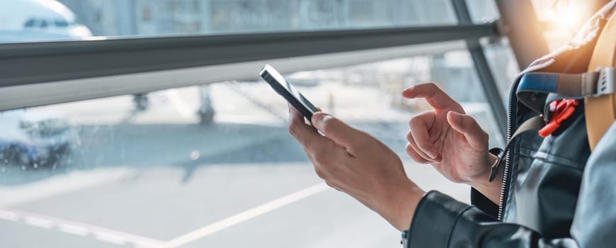 Closeup of a woman using a cell phone at the airport, taking photos or researching travel information..