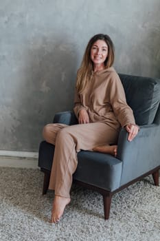 woman in beige pajamas sitting in home chair