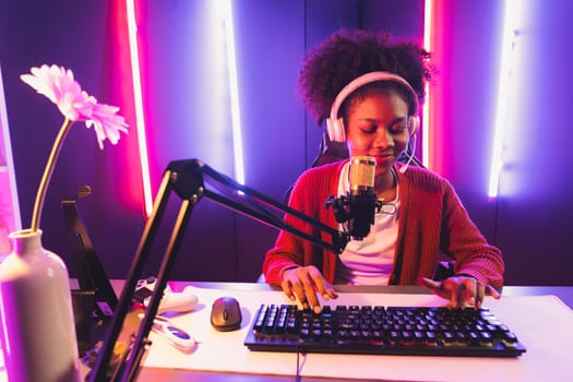 Host channel of gaming streamer, African girl taking, typing with Esport skilled team player and viewers online game in neon color lighting room. Concept of cybersport indoor activities. Tastemaker.