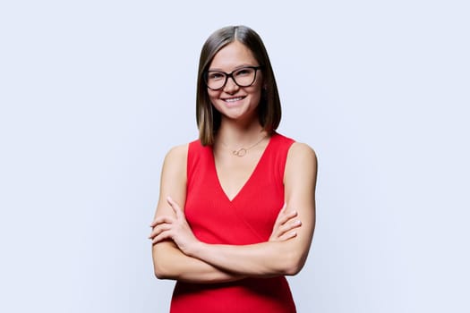 Young smiling happy woman with eyeglasses in red on white background. Successful fashionable female with crossed arms looking at camera. Business work services education, fashion beauty professions