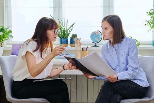 Young woman at a mental therapy session talking to female psychologist in therapist's office. Smiling female patient, help support professional counselor, psychotherapist, mental health youth concept
