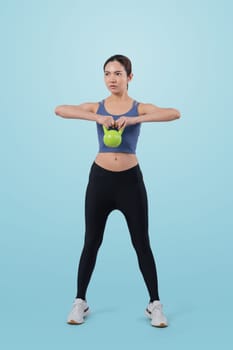 Vigorous energetic woman doing kettlebell weight lifting exercise on isolated background. Young athletic asian woman strength and endurance training session as body workout routine.