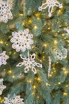 Macrame-style Christmas toys are hanging on the Christmas tree. Toys in the form of snowflakes. Handmade eco-style decor. New Year and eco-friendly concept