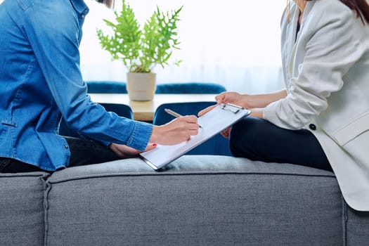 Close-up of hands of psychologist and patient with clipboard. Therapy, psychology, psychotherapy, mental health concept