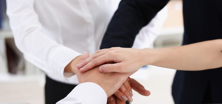 Group of people in suits crossed hands in pile for win closeup. White collar leadership high five cooperation initiative achievement corporate life style friendship deal heap stack concept