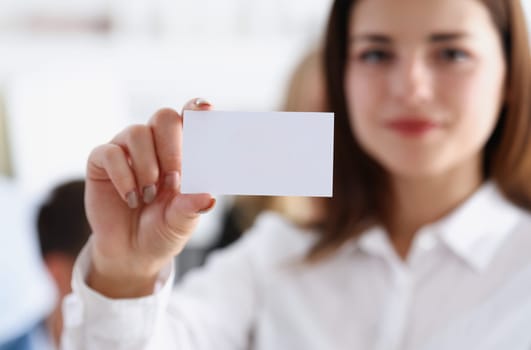 Female hand in suit give blank calling card to visitor closeup. White collar partners company name exchange executive or ceo introducing at conference product consultant sale clerk concept