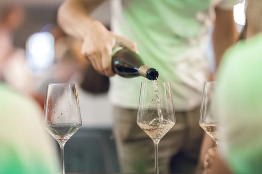 A man pours wine into wine glasses