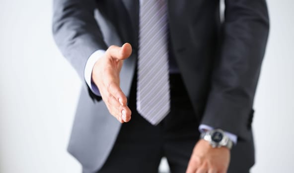 Man in suit and tie give hand as hello in office closeup. Friend welcome mediation offer positive introduction thanks gesture summit participate approval motivation male arm strike bargain