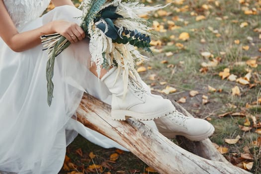 bride wearing white boots holding beautiful autumn bouquet. copy space