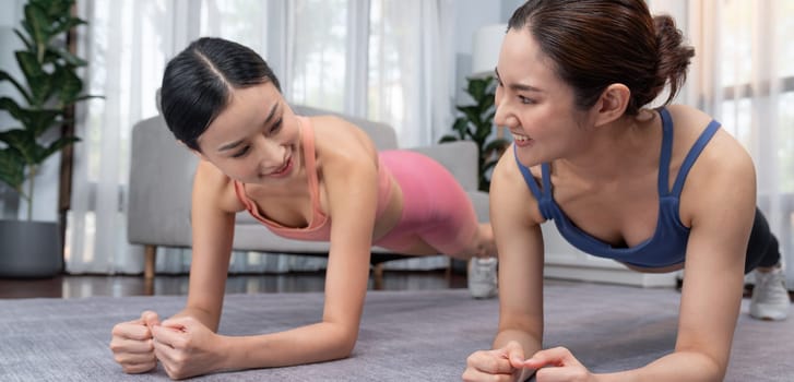 Fit young asian woman planing on the living room floor with her trainer or exercise buddy. Healthy lifestyle workout training routine at home. Balance and endurance exercising concept. Vigorous