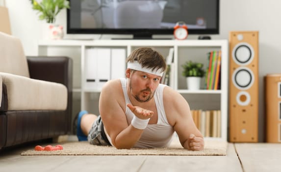 Young man fitness behind a desk is sending you a kiss through the air