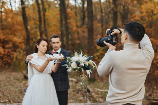 Professional wedding photographer taking pictures of the bride and groom in nature in autumn