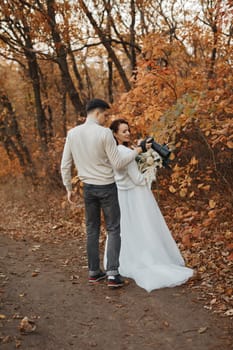 Professional wedding photographer taking pictures of the bride and groom in nature in autumn