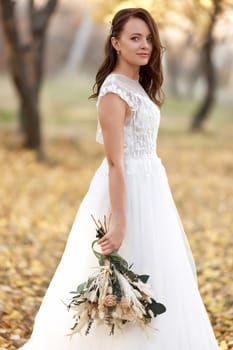 beautiful happy bride holding wedding autumn bouquet in nature