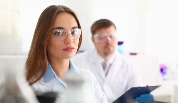 Smiling beautiful technician woman portrait and sample bottle with poison fluid. Medical worker in uniform use reagent tube for virus infection exam or biological toxic reaction drug creation