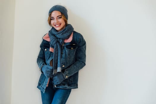 Woman in winter clothes and hat posing on white