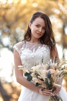 beautiful happy bride holding wedding autumn bouquet in nature