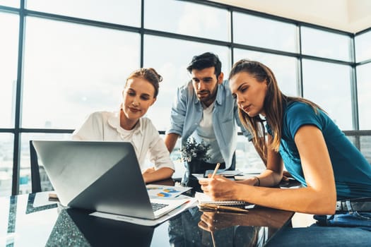 Group of diverse profession business people pointing at laptop displayed idea. Portrait of business team show marketing strategy present by laptop with statistic document scatter on table. Tracery.