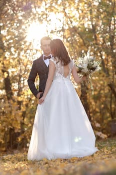 beautiful bride in white wedding dress and groom looking at each other in sunny day