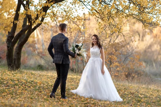 beautiful sensual bride in white wedding dress and groom looking at each other outdoor on natural background