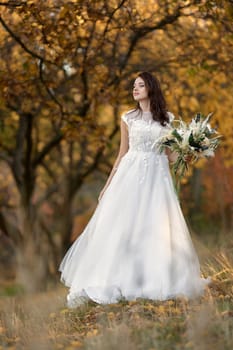 beautiful happy bride holding wedding autumn bouquet in nature
