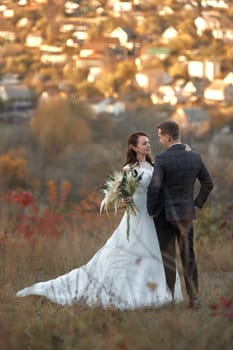 beautiful sensual bride in white wedding dress and groom standing outdoor on natural background