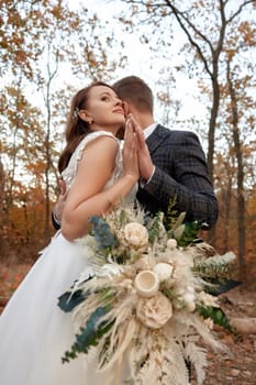 beautiful sensual bride in white wedding dress and groom standing outdoor on natural background