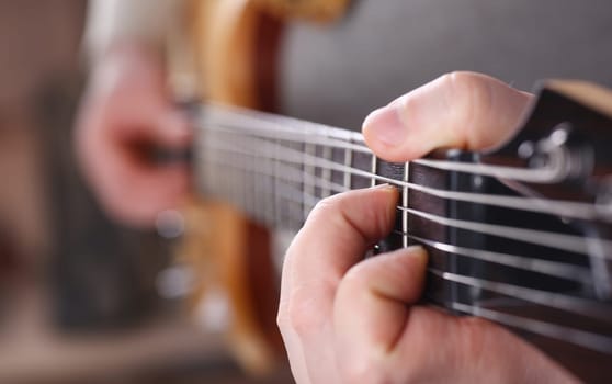 Male arms holding and playing classic shape wooden electric guitar closeup. Six stringed learning musical school education art leisure electrical vintage stage shop having fun enjoying hobby concept