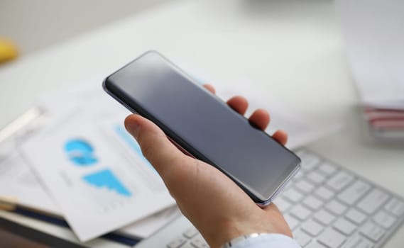 A businessman holds a new smartphone in his hand The mobile application market shows a display you can insert your image for advertising or financial statistics.
