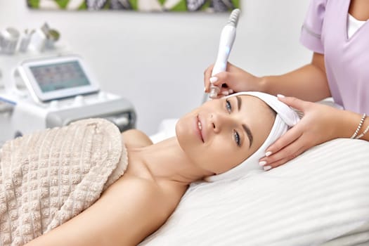 cosmetologist making procedure microdermabrasion on the face in beauty salon