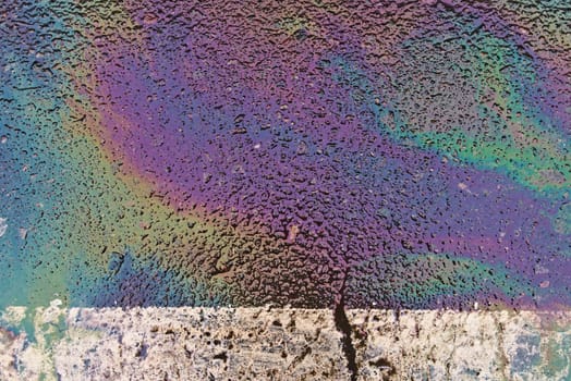 Oil, gasoline, or oil spill on wet asphalt with a parking lot and a dividing line