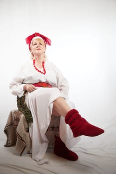 Portrait of cheerful funny adult mature woman solokha. Female model in clothes of national ethnic Slavic style. A stylized Ukrainian, Belarusian or Russian woman poses in a comic photo shoot