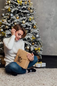 woman opening gifts at christmas tree new year