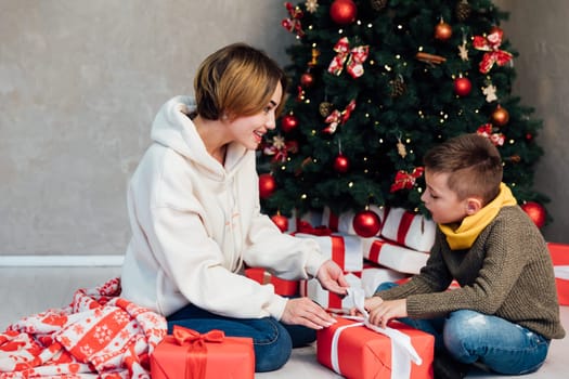 Mom with son at christmas tree with gifts new year